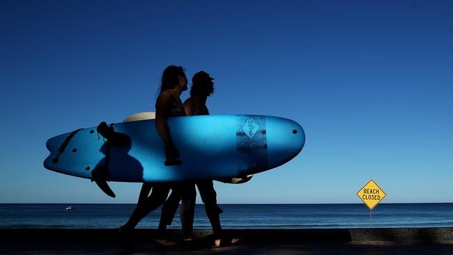 Two young surfers walk past a ‘beach closed’ sign in Sydney. Picture: Getty Images