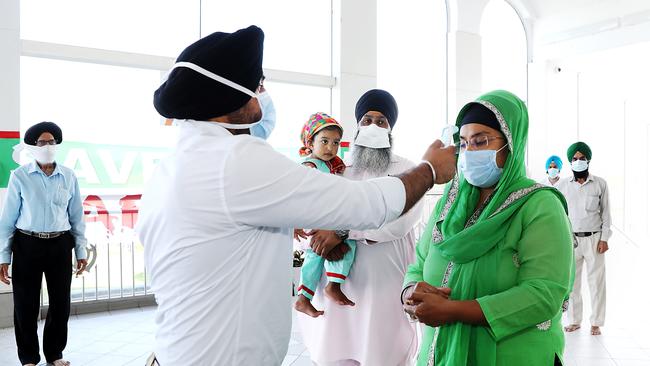 Temperature checking at the Glenwood Gurdwara Sahib Sikh Temple for Amar Singh, his wife, Hasmukh Kaur, and their daughter Saroop Kaur. Picture: Jane Dempster