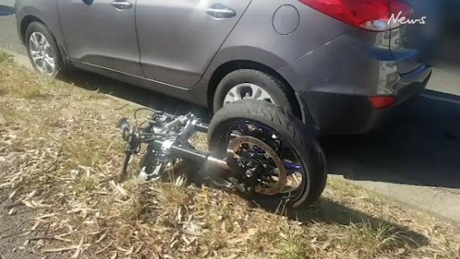 Motorbike jammed under car