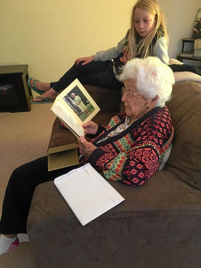 Anne Cox receiving her letter from the queen while her great great niece Bailey Brooks looks on.