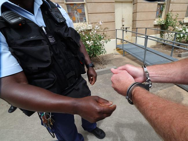 A prisoner’s handcuffs are removed as he enters the yard. Picture: News Corp