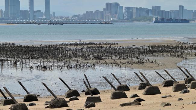 The Xiamen city skyline on the Chinese mainland is seen past anti-landing spikes placed along the coast of Lieyu islet on Taiwan's Kinmen islands. Picture: AFP.