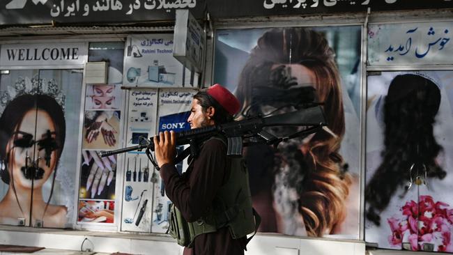 A Taliban fighter walks past a beauty saloon with images of women defaced using a spray paint in Shar-e-Naw in Kabul on August 18, 2021. Picture: Wakil Kohsar/AFP