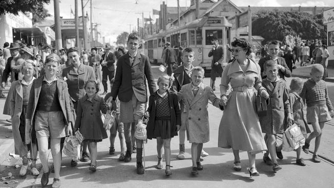 An iconic scene of adults and children holding hands as they walk around the Brisbane Ekka in September 1950.