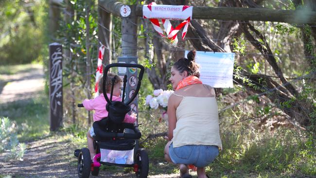 A woman and child place flowers at a makeshift shrine where the remains of a newborn were found. Picture: David Crosling