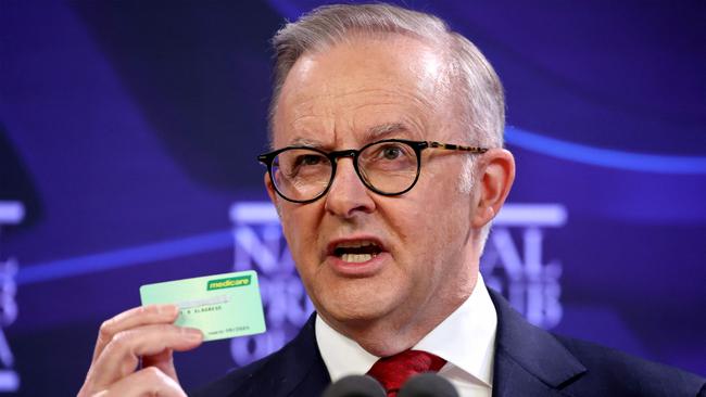 Australia's Prime Minister Anthony Albanese holds up a Medicare card. (Photo by DAVID GRAY / AFP)