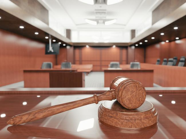 Interior of an empty courtroom with gavel and sounding block on the desk.
