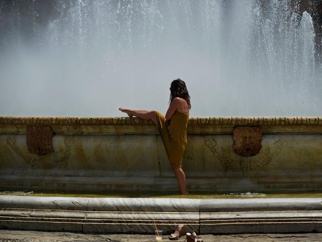 A woman refreshes herself in a fountain at Plaza de Espana, on a hot summer day in Sevilla. Picture: Cristina Quicler