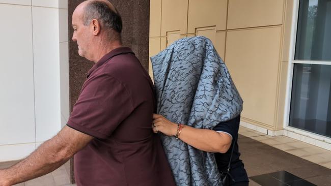 Angela Rita Marcus attempts to hide from a journalist outside of the Supreme Court in Darwin. Ms Marcus is charged with aiding another to commit an offence in relation to the alleged kidnapping of Grace Hughes. Picture: Zizi Averill