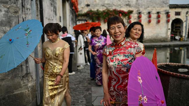 TOPSHOT - Women wearing traditional costumes are seen next to the Hongcun Wangshi ancestral temple in Hongcun village, in eastern China's Anhui province, on May 12, 2024. The ancient village, located in Yi County in Huangshan City, was added to the UNESCO World Heritage Site list in the year 2000 and is known for its scenic lake views and traditional architecture. (Photo by HECTOR RETAMAL / AFP)