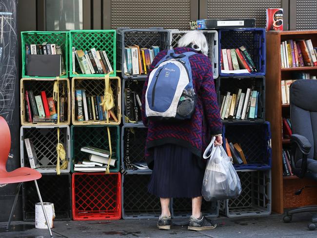 A passer-by looks at the book collection in the tent city “library”. Picture: Toby Zerna