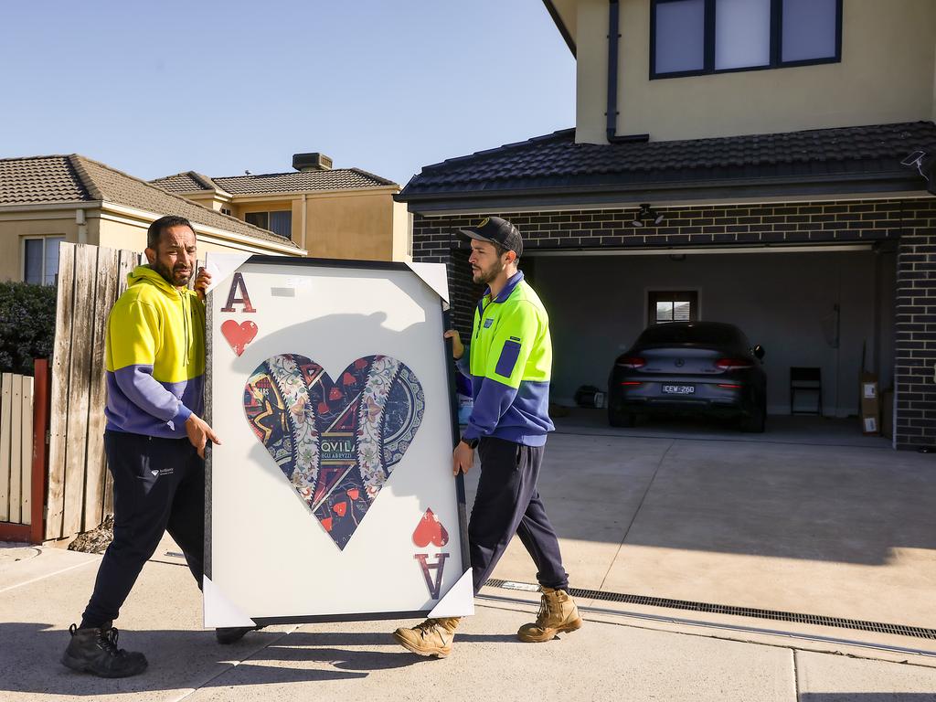 Luxury items, allegedly purchased with stolen money, are wheeled from the home. Picture: Ian Currie