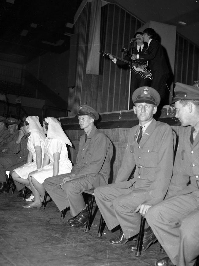 1964: Police and nurses sit stoically in front of the stage — and facing thousands of screaming fans — as The Beatles perform at Festival Hall, Brisbane. File picture