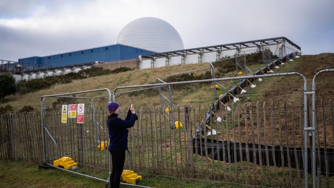 A woman photographs through a fence surrounding the site of Sizewell C nuclear power station in Sizewell, United Kingdom. This week the UK government announced plans for a new nuclear power station to be built in the UK by 2050. Picture: Carl Court/Getty Images