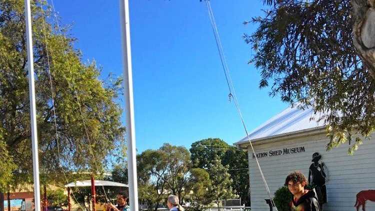 Year 10 students Jaqwon Murray and Pharrell Chapman raise the flags at The Ration Shed Museum. Picture: Murgon State High School