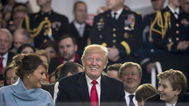 President Donald Trump shares a laugh with first lady Melania Trump and son Barron Trump as they sit in the reviewing stand during Trump's inaugural parade. Picture: AP