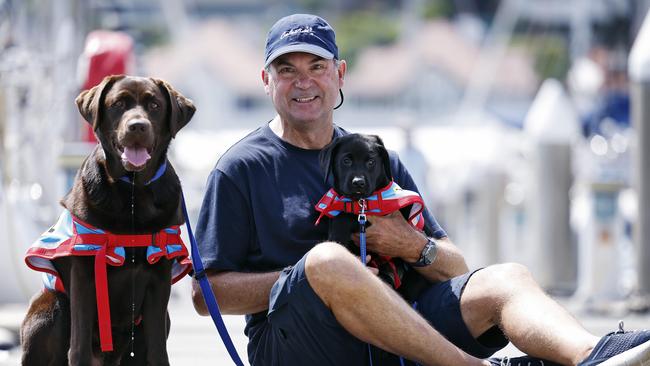 Sam Haynes pictured with dogs Cosmo (puppy on lap) and Jojo (left) from Assistance Dogs Australia. Picture: Sam Ruttyn