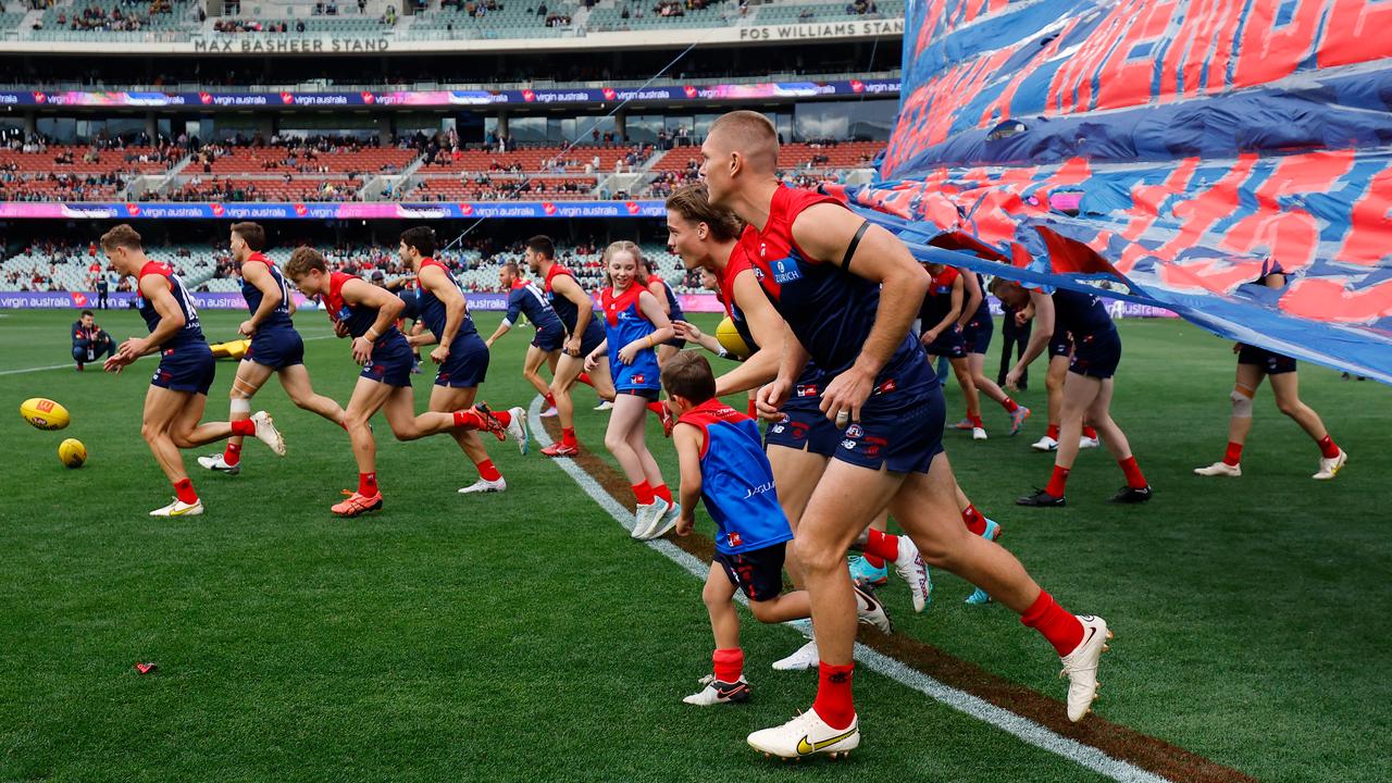 The Demons enter through the banner. Picture: Dylan Burns