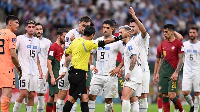 Uruguayan players argue with the referee after a VAR penalty decision.