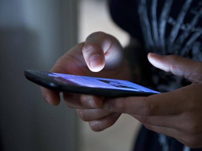 Hands holding smartphone in the dark.