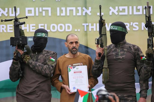 Hamas fighters escort Israeli hostage Eli Sharabi on a stage before handing him over to a Red Cross team in Deir el-Balah, central Gaza, on February 8, 2025 under a truce deal