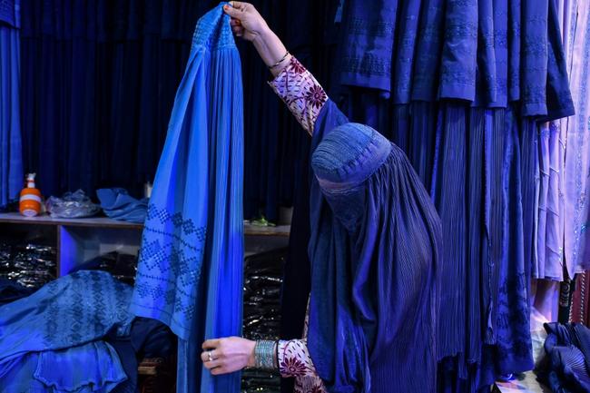 An Afghan shops in Mazar-i-Sharif: the all-enveloping blue burqa with a face mesh has become a symbol of the Taliban's oppression of women