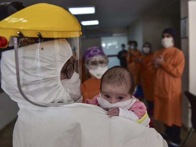 In this Monday, May 11, 2020 photo,  staff applaud as a nurse, wearing a face mask and a shield to protect against coronavirus, carries baby Amine Tepe who was infected with COVID-19, as she is taken out of the intensive care unit following a week's treatment, at an Istanbul hospital. Tepe was diagnosed with coronavirus  when she was 37 days old after contracting the virus from her parents according to doctors. The baby has been moved to a hospital ward. Turkey's government announced a "normalization plan" as the number of new virus cases declined last week but warned of tougher measures, if infections go up again. (Ibrahim Mase/DHA via AP)