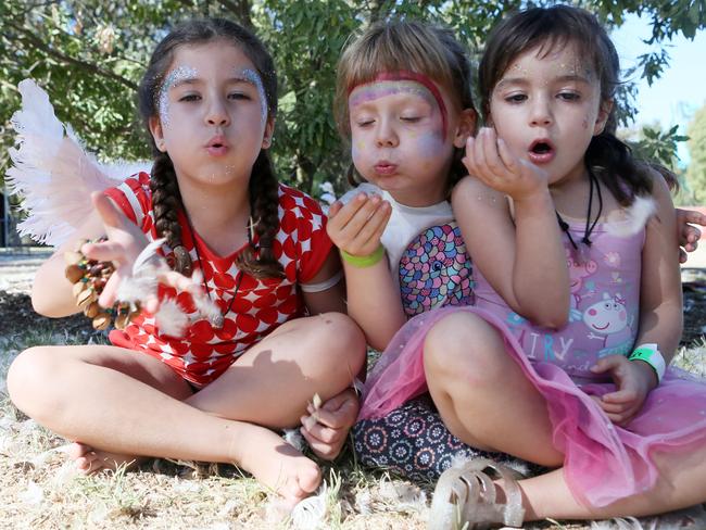 Ayana, 5, with sister Cali, 3, and Rosie, 5, play in the feathers dopped over the Womadelaide crowd by Gratte Ciel's Place des Anges. Picture: AAP / Emma Brasier