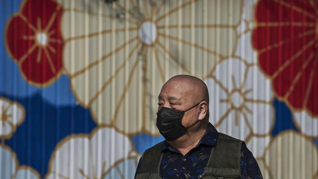 A Chinese man wears a protective mask as he walks while enjoying the spring weather at a park in Beijing. Picture: Kevin Frayer/Getty