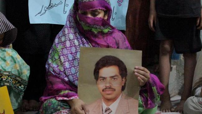 Safia Bano with a picture of her husband Imdad Ali while she protests with other family members in Burewala, in central Pakistan.