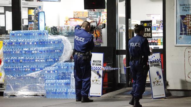 Police at the service station in Lidcombe. Picture: Steve Tyson