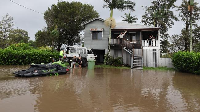 Flooding on the Gold coast in the aftermath of Cyclone Alfred. Stapylton homes surrounded by floodwaters..Leigh Kerslake and family watch the water with their jetski tied to the letterbox Picture Glenn Hampson