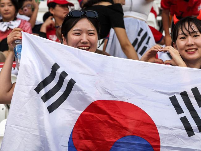 South Korea's supporters pose for a picture with their national flag during the AFC U23 Asian Cup Qatar 2024 Group B match between Korea and Japan at Jassim Bin Hamad Stadium in Doha on April 22, 2024. (Photo by KARIM JAAFAR / AFP)