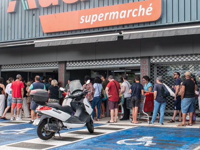 People wait outside supermarkets in hope of finding food.