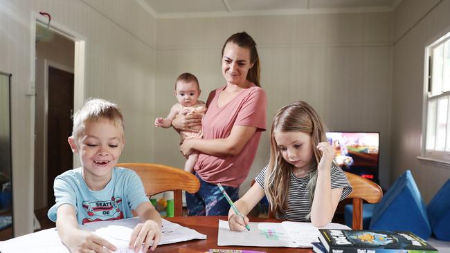 Aeroglen siblings Oskar Szenczy, 7, and Olivia Szenczy, 5, complete schoolwork at their kitchen table with the help of their mother Ashley Szenczy (pictured with her daughter Valerie Ferguson, 6 months). Ashley would prefer to see her two eldest resume school in their classrooms at Edge Hill State School, rather than try to juggle home schooling and baby duties. Picture: Brendan Radke