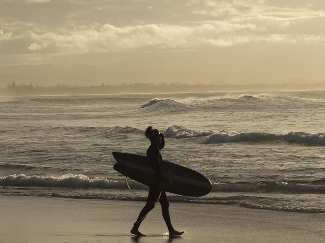 BYRON BAY, AUSTRALIA - JUNE 11: A surfer enters the water at Wategos Beach on June 11, 2020 in Byron Bay, Australia. Domestic tourists have started to return to Byron Bay following the easing of travel restrictions imposed due to the COVID-19 outbreak. All intrastate travel restrictions were lifted in NSW on June 1, allowing people to travel to regional areas within the state. Although borders between NSW, the ACT and Victoria remain open, Australians have been asked not to holiday interstate. Queensland, Western Australia and Tasmania's state borders remain closed, while South Australia is only open to travellers from WA, Tasmania and the Northern Territory while interstate arrivals to the Northern Territory must self isolate for 14 days. (Photo by Brook Mitchell/Getty Images)