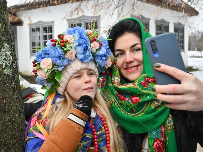 A woman and a young girl, wearing traditional Ukrainian clothes, pose for selfies as they take part in Christmas celebrations in Pyrogove, near Kyiv on December 25, amid Russian invasion in Ukraine. Picture: AFP