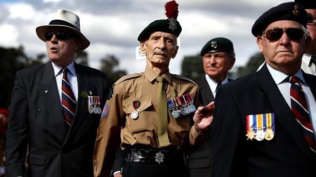 Veterans and family members march during the Anzac Day National Service in front of the A