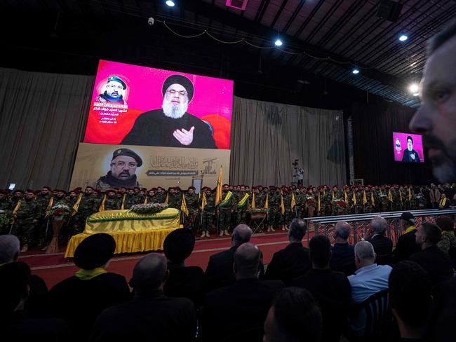 A televised speech by Hezbollah chief Hassan Nasrallah is transmitted on large screens as mourners attend the funeral ceremony of Fuad Shukr in Beirut last week. Picture: AFP