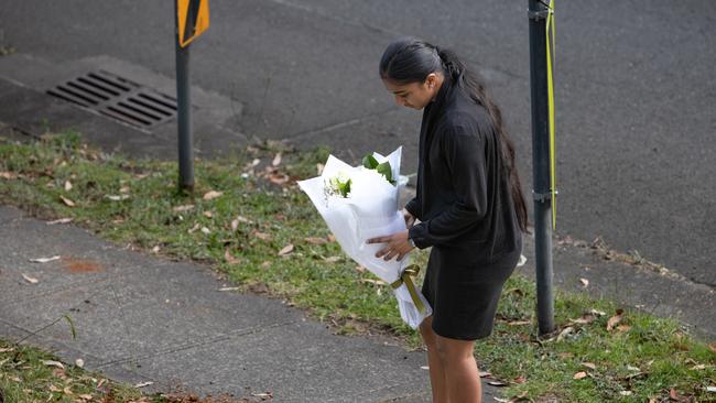 A girl lays flowers at the scene of the collision at Rembrandt St, Carlingford, when a teenager was killed. Picture: Julian Andrews