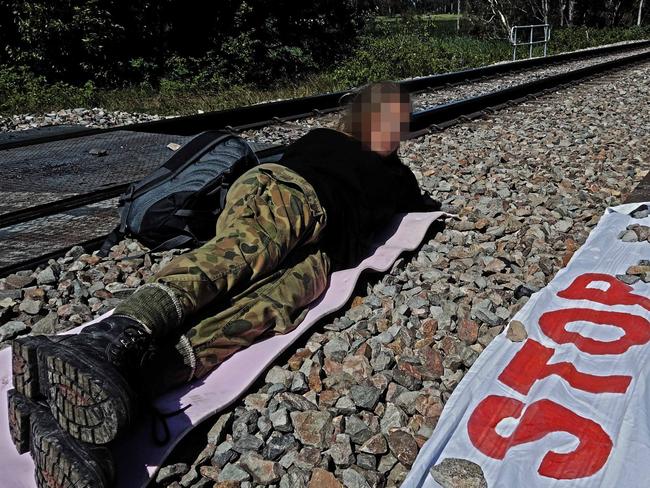 PIXELATED VERSION .. 15/11/2021 Blockade Australia Facebook page posted approximately 1pm.  Emily has been taking action today, halting all rail operations to Newcastle port.  She has locked her arm into a pipe in the rail line since 10am, intending to stay until removed by police. This is the second action today disrupting this critical infrastructure, as part of a sustained campaign of nonviolent blockading tactics to defend the earth against ecological collapse., "Our planet's life support systems are collapsing, a crisis driven by the machine we call Australia. We have no choice but to get in the way" Emily said.  Source: https://www.facebook.com/BlockadeAustralia/photos/pcb.292100289452520/292100032785879/