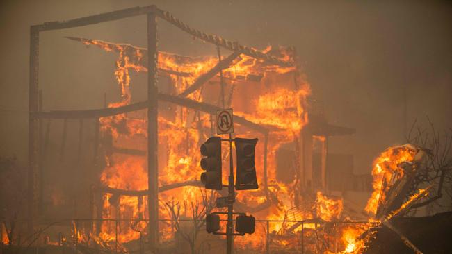 LOS ANGELES, CALIFORNIA - JANUARY 8: Flames from the Palisades Fire burn a building on Sunset Boulevard amid a powerful windstorm on January 8, 2025 in the Pacific Palisades neighborhood of Los Angeles, California. Fueled by intense Santa Ana Winds, the Palisades Fire has grown to overÂ 15,000Â acres and 30,000 people have been ordered to evacuate while a second major fire continues to burn near Eaton Canyon in Altadena.   Apu Gomes/Getty Images/AFP (Photo by Apu Gomes / GETTY IMAGES NORTH AMERICA / Getty Images via AFP)