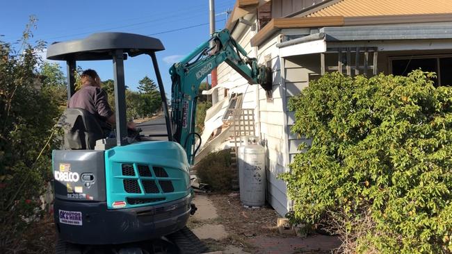 The pair filmed themselves on a hired excavator, ripping out the fireplace and pulling down the walls. Picture: Supplied.