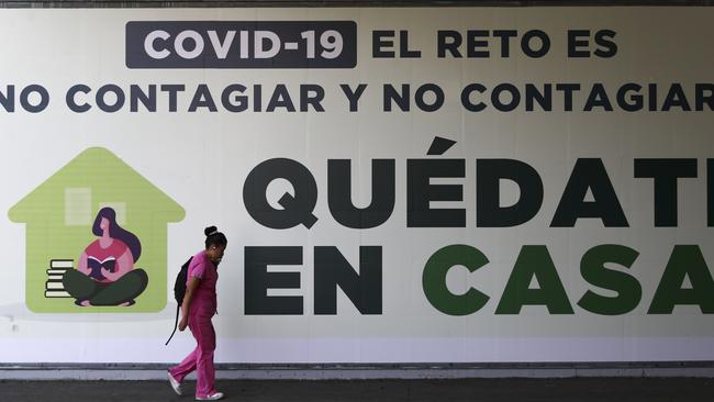 A woman walks past a sign in Mexico City that translates in English to “COVID-19. The challenge is not to get it and not spread it. Stay home.” Picture: AP