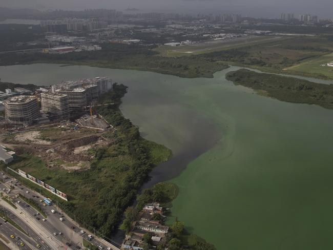 This July 27, 2015 aerial photo shows fluorescent green waters in the Marapendi Lagoon, in Rio de Janeiro, Brazil. The lagoons that hug the Olympic Park and which the government’s own data shows are among the most polluted waters in Rio were to be dredged, but the project got hung up in bureaucratic hurdles and has yet to start. (AP Photo/Leo Correa)