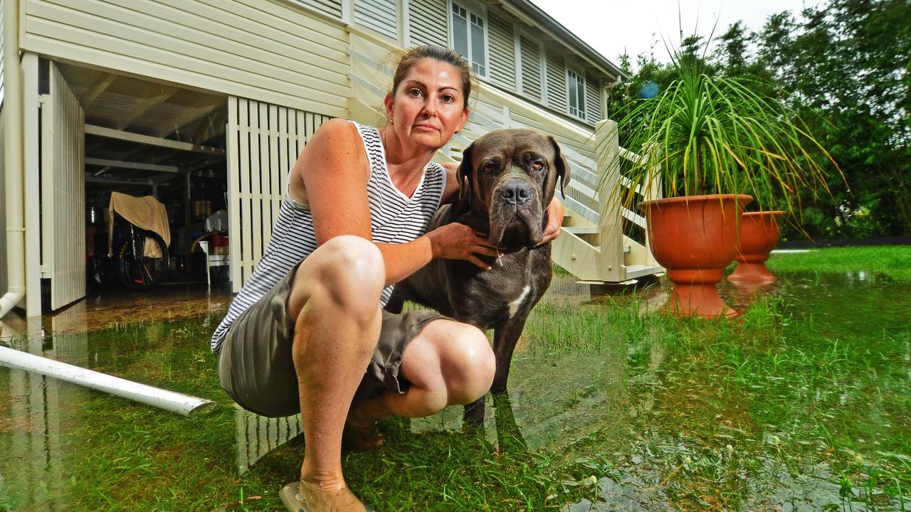 Tori Walker stands out the front of her flooded Queens Road home in Railway Estate with dog Tia, 5. Picture: Zak Simmonds