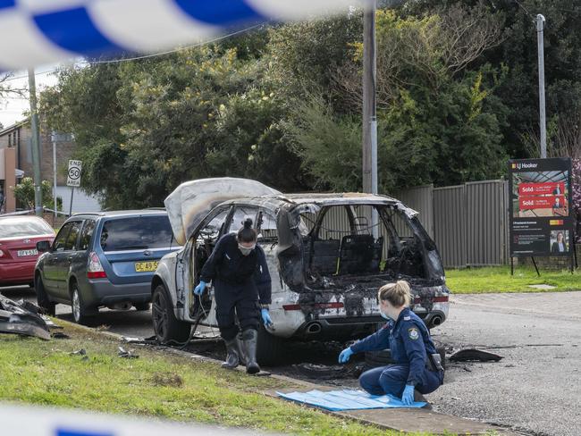 Forensics police officers examine the scene of a burnt out car used in the fatal shootings. Picture: Monique Harmer