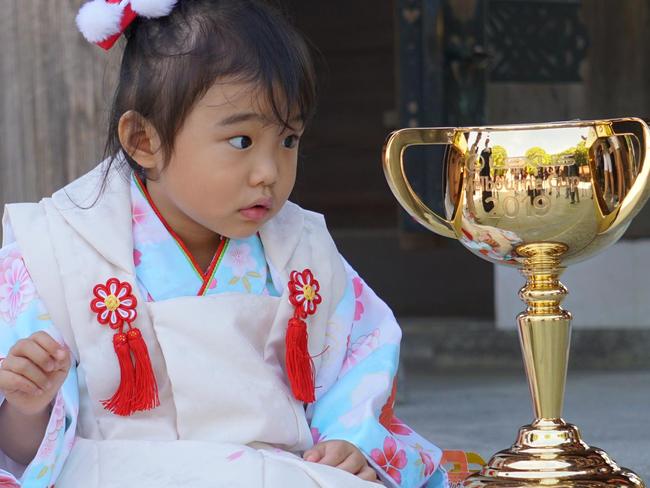 A young Japanese girl admires the $200,000 Lexus Melbourne Cup in Tokyo. Picture: Nicolas Datiche