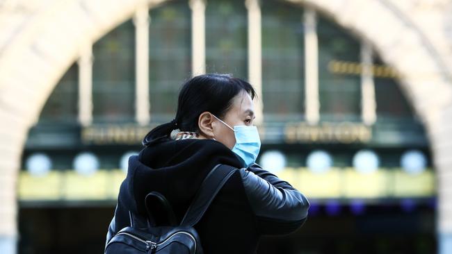 A woman outside Flinders Street Station acts on Victorian Premier Daniel Andrews’s advice and wears a face mask. Picture: Aaron Francis