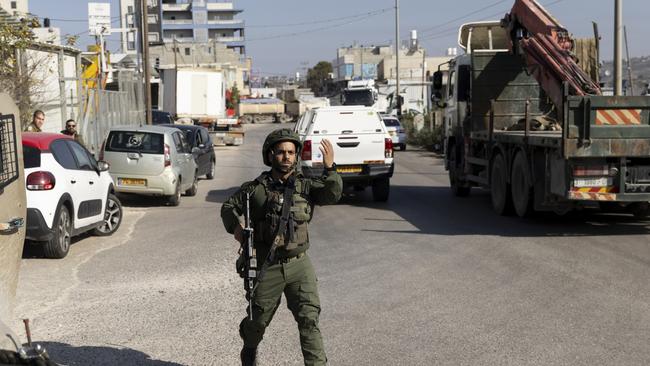 An Israeli soldier directs traffic following a shooting attack in the Palestinian village of Al-Funduq, West Bank. Picture: Getty Images.